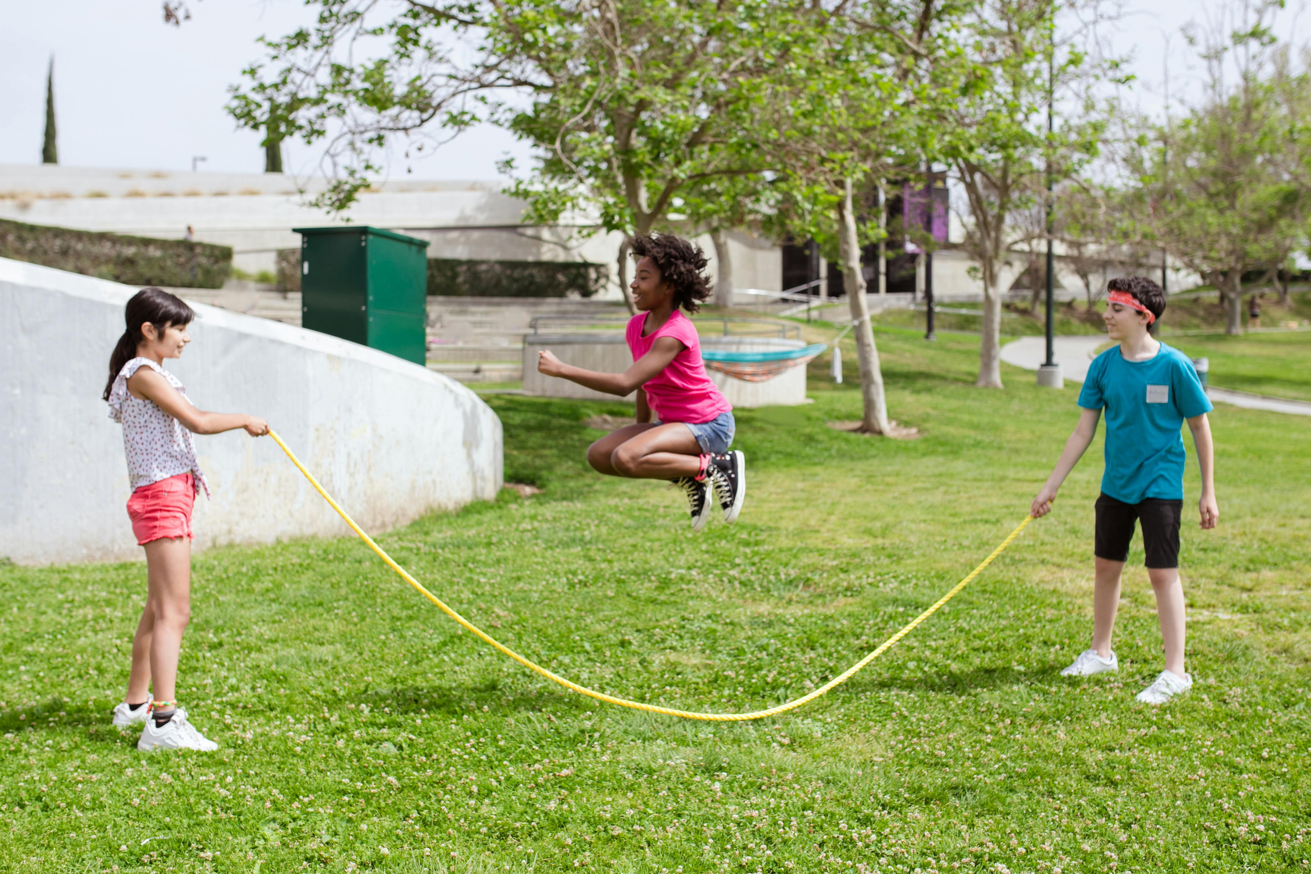 Kids playing jump rope on a grassy field